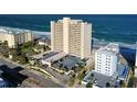 An exterior daytime view of a condo on the beach overlooking the ocean and parking lot from an elevated angle at 89 S Atlantic Ave # 1004, Ormond Beach, FL 32176