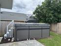 Backyard featuring a gray hot tub with a cover next to an above-ground pool and surrounded by privacy fencing at 146 Via Madrid Dr, Ormond Beach, FL 32176