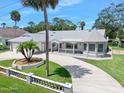Charming single-story home with a gray roof, circular driveway, and a well-manicured front yard with palm trees at 1650 Riverside Dr, Daytona Beach, FL 32117