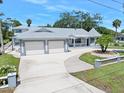 Charming single-story home featuring a gray roof, two-car garage, circular driveway, and landscaped front yard at 1650 Riverside Dr, Daytona Beach, FL 32117