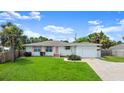 Beautiful single-story home featuring a well-maintained lawn, palm trees, shuttered windows, and an attached garage at 1026 Bel Aire Dr, Daytona Beach, FL 32118