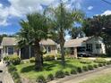 A residential view of a well-landscaped house with palm trees and an American flag at 1218 Daytona Ave, Daytona Beach, FL 32117
