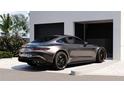 Sleek gray luxury car parked on paved driveway with view of garage entrance accented by a lush green bush with pink flowers at 2360 Ocean Shore Blvd # 27, Ormond Beach, FL 32176