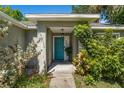 Close-up of the entryway featuring a blue front door and verdant, tropical landscaping at 2531 Needle Palm Dr, Edgewater, FL 32141
