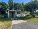 Charming single-story home featuring a carport, well-maintained lawn, and a mature tree providing ample shade at 264 Sherwood Ln, Daytona Beach, FL 32117