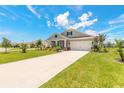 Beautiful home boasts a long driveway, lush green lawn, and colorful landscaping under a sunny sky with scattered clouds at 2836 Monaghan Dr, Ormond Beach, FL 32174