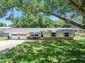 Charming single-story home with yellow siding, brick accents, well-manicured lawn, mature trees, and an attached two-car garage at 1505 Valencia Ave, Daytona Beach, FL 32117
