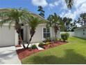 Inviting single-story home with a manicured lawn, featuring palm trees and colorful flowerbeds at 465 Dahoon Holly Dr, Daytona Beach, FL 32117