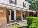 Inviting covered front porch with brick columns, cozy seating, and a stylish black front door at 506 Dorset Cir, South Daytona, FL 32119