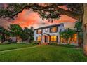 Elegant two-story home with manicured lawn, mature trees, and a brick walkway leading to the inviting entrance under a vibrant sunset at 1221 Gamble Pl, Daytona Beach, FL 32118