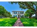Classic two-story home with lush green lawn and a brick walkway leading to the charming front door, shaded by mature trees at 1221 Gamble Pl, Daytona Beach, FL 32118