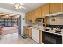 Efficient kitchen featuring light-colored cabinets, tile floor, modern appliances, and an opening to an enclosed patio at 1 Beechwood Dr, Ormond Beach, FL 32176