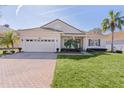 Tan house with a tile roof, two-car garage, and lush landscaping at 2441 Prairie Dunes, Clermont, FL 34711