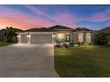 Attractive home exterior at dusk, showcasing landscaping and two-car garage at 1786 Red Clover Ln, The Villages, FL 32163