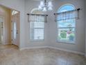 Dining area features arched windows, neutral paint, tile flooring, and chandelier at 1751 Ashwood Run, The Villages, FL 32162