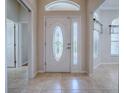 Bright foyer features decorative glass front door, transom window, tile flooring and entry to other rooms at 1751 Ashwood Run, The Villages, FL 32162