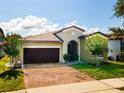 Charming single-story home with a two-car garage, a well-manicured lawn, and a brick-paved driveway at 9342 Oglethorpe Dr, Groveland, FL 34736