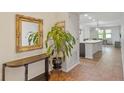Bright hallway featuring an ornate mirror, indoor plants, and tile flooring leading to an open-concept living space at 9342 Oglethorpe Dr, Groveland, FL 34736