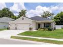 Beautifully landscaped home with a three-car garage, featuring a well-maintained lawn and a cozy front entrance at 6834 Mossy Oak Ln, Lakeland, FL 33810