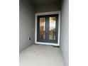 Elegant front door with glass panes and dark trim, complemented by neutral siding and a clean entrance at 2311 Juniper Berry Dr, Minneola, FL 34715