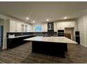 Modern kitchen with black lower and white upper cabinets, large island, and stainless steel appliances at 2311 Juniper Berry Dr, Minneola, FL 34715