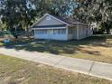 Light tan house with a brown roof and mature trees at 1010 S Grove St, Eustis, FL 32726