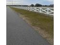 Street view of property showing asphalt road and fenced yard with a decorative white 'X' patterned wooden fence at 10739 Fiesta St, Clermont, FL 34711