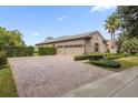 Two-car garage with paver driveway and landscaped hedges at 25499 Hawks Run Ln, Sorrento, FL 32776