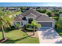 Beautifully landscaped home featuring mature palms, a pristine lawn, and a wide driveway leading to a spacious three-car garage at 1338 Neuport Path, The Villages, FL 32163