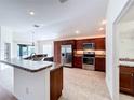 Modern kitchen featuring stainless steel appliances, dark wood cabinetry, and a breakfast bar with granite countertops at 1338 Neuport Path, The Villages, FL 32163