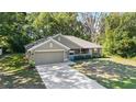 Well-maintained single story home with a lush green lawn and mature trees, featuring a cozy covered front porch at 8566 Se 156Th Pl, Summerfield, FL 34491