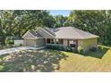 Well-maintained single story home with a lush green lawn and mature trees, featuring a covered front porch at 8566 Se 156Th Pl, Summerfield, FL 34491