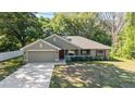 Inviting single-story home with manicured lawn and mature trees, featuring a cozy covered porch and two-car garage at 8566 Se 156Th Pl, Summerfield, FL 34491
