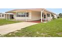Single-wide manufactured home with carport and well-maintained lawn at 1209 Apache Cir, Tavares, FL 32778