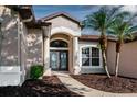 Close up of the front entrance, featuring double glass doors and decorative landscaping at 27303 Gingerbread Pl, Leesburg, FL 34748