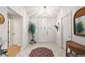 Bright foyer with white tile flooring, decorative plant, and a wicker table to give an inviting view when entering the home at 1306 De La Garza Pl, The Villages, FL 32162