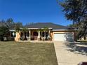 One-story house featuring a gray roof, a white garage door, and a spacious lawn at 15921 Hanson View Dr, Tavares, FL 32778