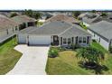 Aerial view of a well-maintained single-story home with manicured lawn, landscaping, and a two-car garage at 736 Jones Ln, The Villages, FL 32163