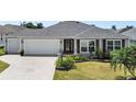 Charming single-story home with an attached two-car garage, manicured lawn, and decorative driveway at 736 Jones Ln, The Villages, FL 32163