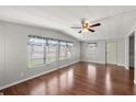 Bright living room featuring wood floors, a ceiling fan, and multiple windows with decorative valances at 1605 W Schwartz Blvd, The Villages, FL 32159