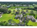 Aerial shot highlighting a beautiful home surrounded by green lawns and mature trees within a golf community at 557 Dowling Cir, Lady Lake, FL 32159