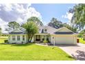 Charming single-story home with manicured lawn, mature trees, and a welcoming front porch at 557 Dowling Cir, Lady Lake, FL 32159