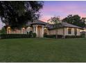 Stunning home exterior featuring lush lawn, manicured landscaping, and elegant architectural details at sunset at 39705 Grove Hts, Lady Lake, FL 32159