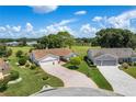 Spacious homes with well-manicured lawns and brick driveways nestled in a golf course community under a bright, cloudy sky at 4830 Summerbridge Cir, Leesburg, FL 34748