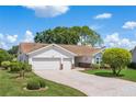 Charming one-story home featuring a brick driveway, attached two-car garage, and beautiful landscaping under a bright, sunny sky at 4830 Summerbridge Cir, Leesburg, FL 34748