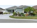 Charming single-story home featuring a beautifully landscaped front yard with lush greenery and a curved driveway at 2968 Wotring Way, The Villages, FL 32163