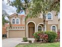 Two-story home featuring a clay tile roof, arched entry, two-car garage, and mature landscaping at 436 Orange Cosmos Blvd, Davenport, FL 33837