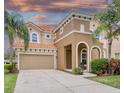 Two-story home featuring a clay tile roof, arched entry, two-car garage, and mature landscaping at 436 Orange Cosmos Blvd, Davenport, FL 33837