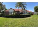 Inviting single-story home with a lush green lawn, manicured hedges, and a lovely red tile roof at 39331 Treeline Dr, Lady Lake, FL 32159