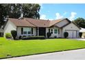 Well maintained house featuring a brown roof, neutral siding and manicured lawn at 6410 Tildon Ct, Leesburg, FL 34748